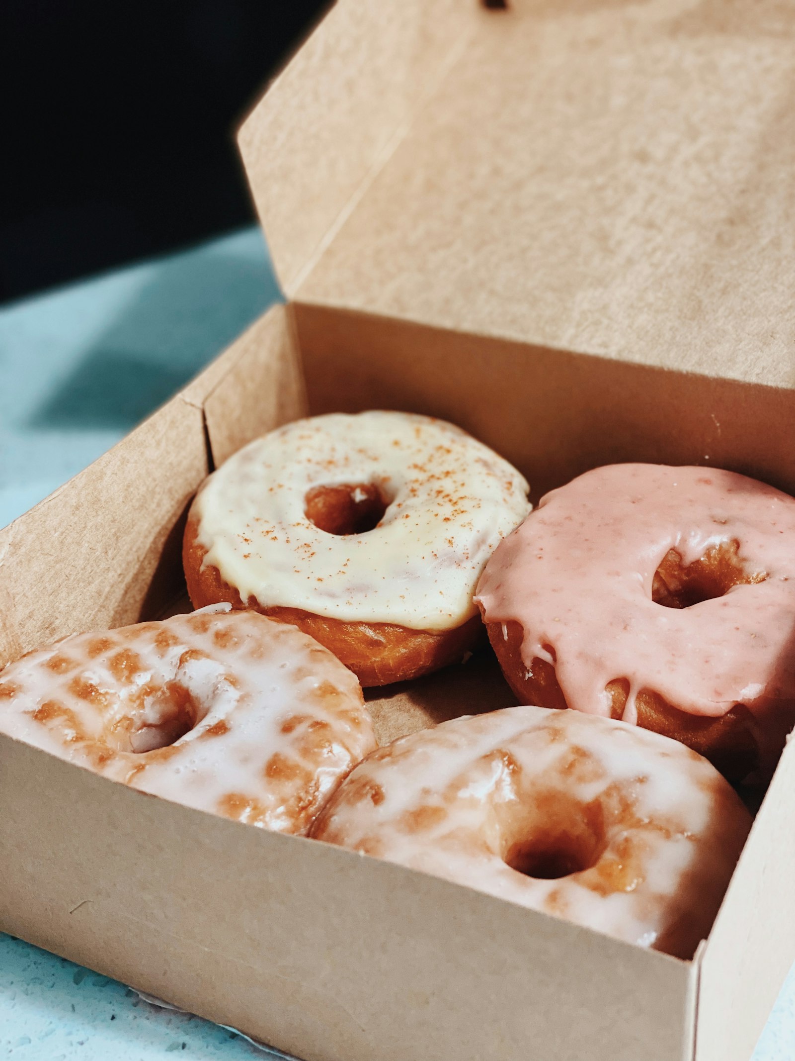 Four glazed donuts in an open kraft box